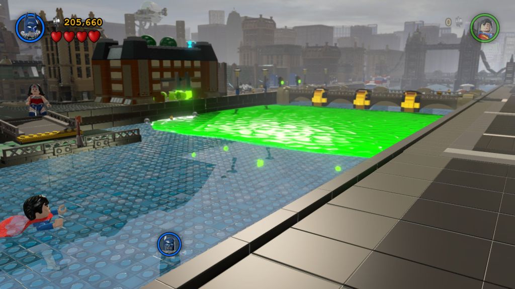game screenshot, a lego version of a miniature london, a toxic spill in the thames from a blown up battersea power station, batman, superman, wonder woman are there 